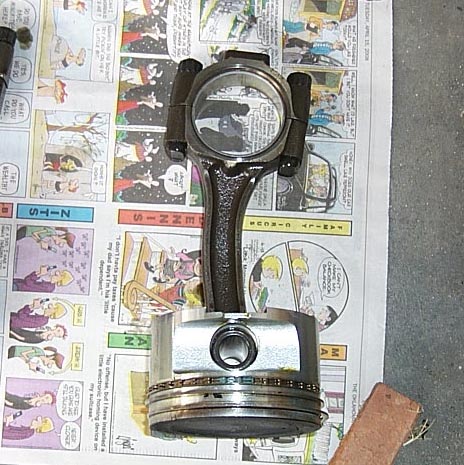 1988 Pontiac Fiero - A disassembled engine part, a piston and connecting rod, rests on a page of comics.
