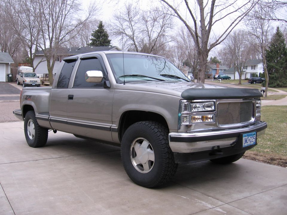 Tan GMC extended-cab pickup with brush hood and Z71 trim in a driveway