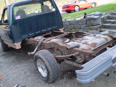 1995 Ford F-150 - The rear chassis of a green Ford F-150 truck, showing significant rust on the frame and fuel tank.