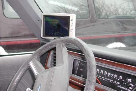 1988 Ford LTD Crown Victoria - Interior shot from the driver's seat showing an aftermarket LCD video screen mounted on the dash top playing a video image, beside a gray f…