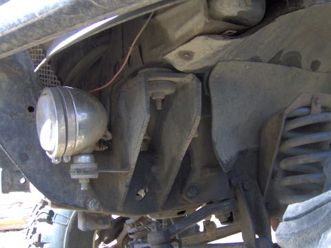 1992 Ford F-350 - Close-up of the undercarriage, highlighting the suspension components and an auxiliary spotlight attached to the frame.