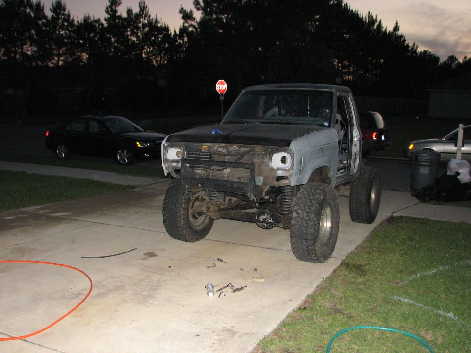 Gray truck with lifted suspension and large tires, front end disassembled