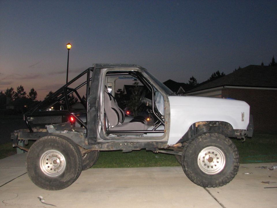 Custom off-road SUV with roll cage, open doors, and large tires