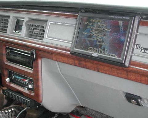 1988 Ford LTD Crown Victoria - Dashboard with woodgrain trim showing aftermarket stereo head units and a small flip-up video screen above the glove box.