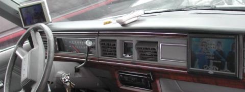 1988 Ford LTD Crown Victoria - Wide interior shot across the gray dashboard of a 1980s full-size Ford sedan, showing woodgrain trim, a horizontal-sweep speedometer, colum…