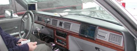 1988 Ford LTD Crown Victoria - Interior shot across the gray dashboard of a full-size Ford sedan, showing the four-spoke steering wheel, woodgrain trim and an aftermarket…