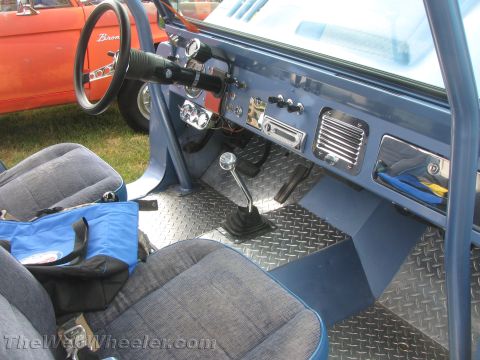 1968 Ford Mustang - The interior of a blue off-road vehicle features diamond plate flooring and a manual transmission, with another vehicle visible outside.
