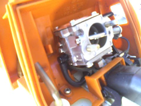 2000 Chevrolet Tahoe - Close-up of a carburetor assembly within an orange housing, with visible hoses and metal components.