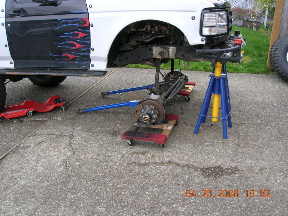 Ford truck front end raised on jack stands, suspension removed. Flames decal on door