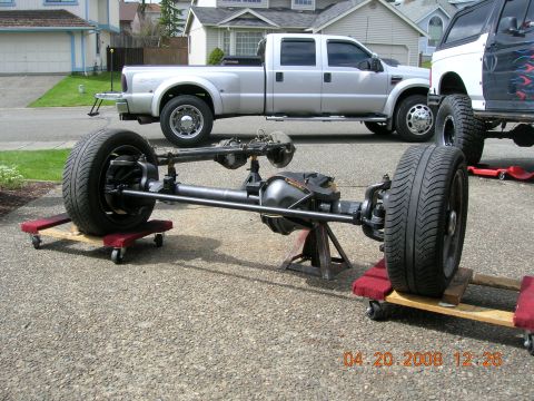 1996 Ford Bronco - A front axle assembly is displayed on dollies, with other vehicles visible in the background.