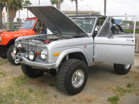 1968 Ford Mustang - A silver Ford Bronco is parked with its hood and driver's door open, next to another Bronco.