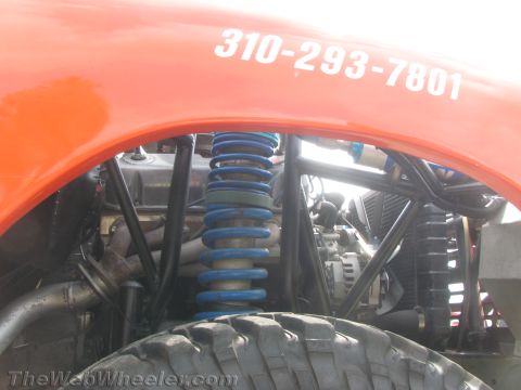 1968 Ford Mustang - Close-up of an off-road vehicle's suspension and engine bay, showing a phone number on the fender.
