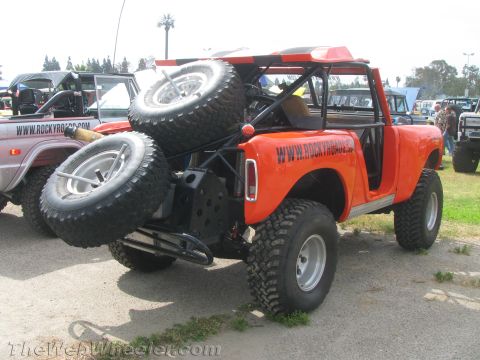 1968 Ford Mustang - Modified off-road vehicle with spare tires and roll cage, parked outdoors with other vehicles.