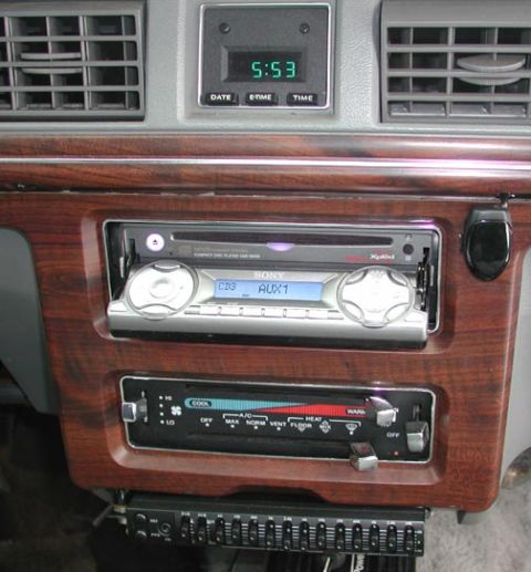 1988 Ford LTD Crown Victoria - Center-stack detail of an older Ford showing a Sony aftermarket CD receiver displaying 'CD3 AUX1' in blue, mounted in a woodgrain dash trim…