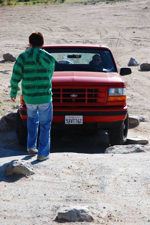 1995 Ford Bronco - 1995 Ford Bronco parked on a dirt path with a person approaching it.