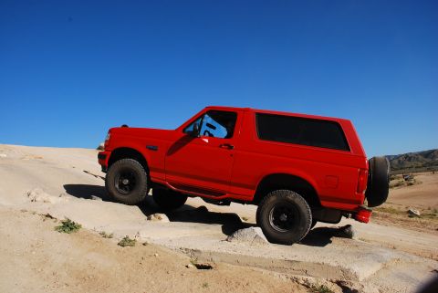 1995 Ford Bronco - Red 1995 Ford Bronco navigating rocky terrain off-road.