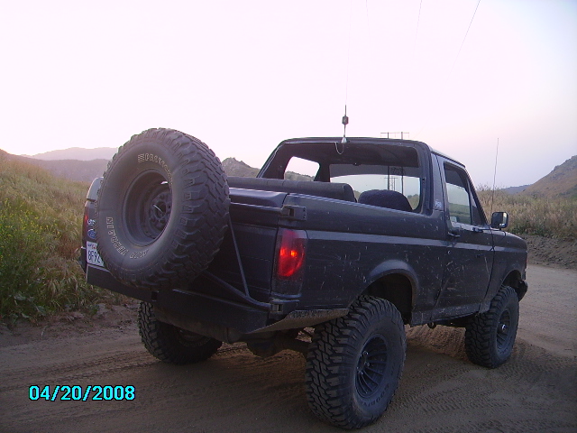 1990 Ford Bronco parked on dirt road, rear view with spare tire mounted externally