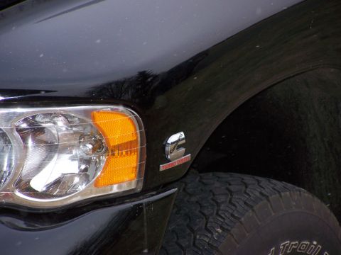 2005 Dodge 2500 - Close-up of a black truck's fender, showing the headlight and a Cummins Turbo Diesel badge, consistent with a 2005 Dodge 2500.