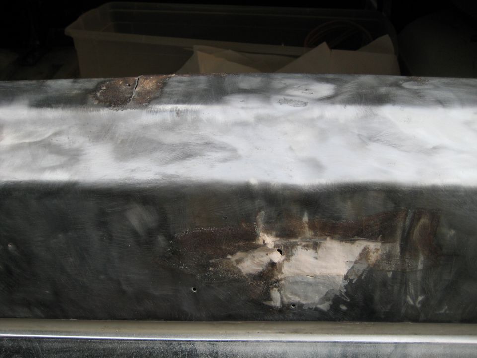 metal body panel being prepped for repair, showing rust and filler