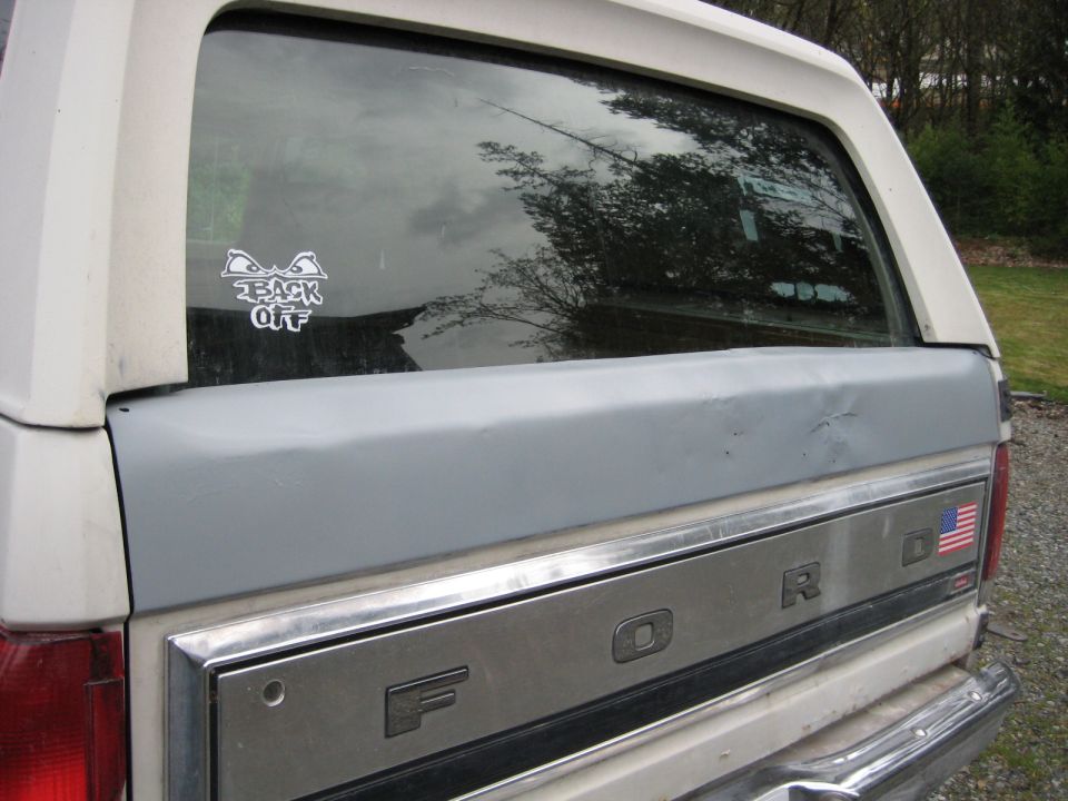 White 1980 Ford Bronco rear, showing tailgate with 'FORD' script and American flag decal