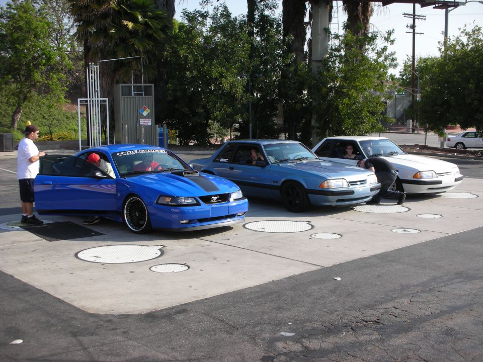 Blue Ford Mustang with black racing stripes and black rims, driver's door open