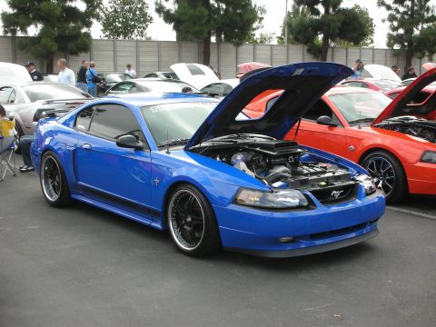 1992 Ford Crown Victoria - Blue Ford Mustang with hood open at a car show, parked next to an orange Mustang.