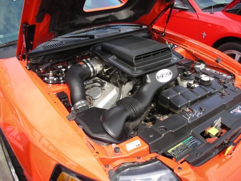1992 Ford Crown Victoria - Engine bay of an orange car an aftermarket intake system and a hood scoop. Another car is in the background.