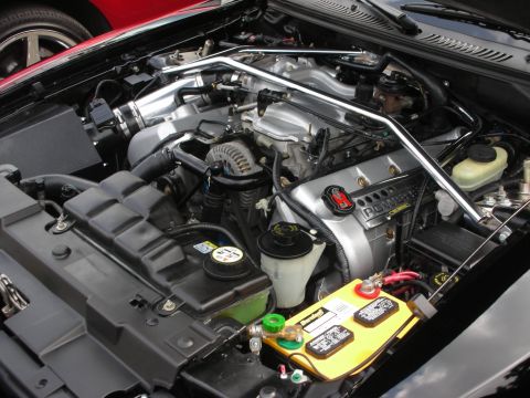 1992 Ford Crown Victoria - Close-up of a V8 engine bay, a chrome strut tower brace and a yellow battery.