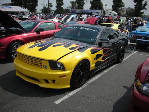 1992 Ford Crown Victoria - A modified yellow and black Saleen Mustang with flame graphics is parked at a car show.