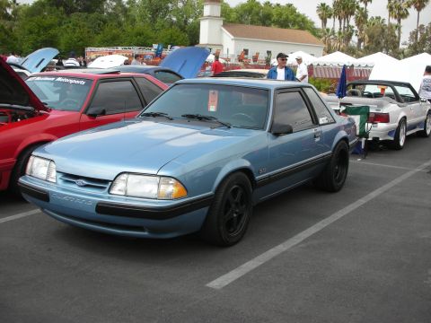 1992 Ford Crown Victoria - A light blue Ford Mustang is parked at a car show, with other vehicles visible in the background.