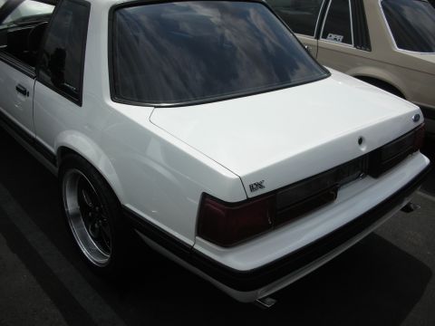 1992 Ford Crown Victoria - Rear view of a white coupe with a black trim line and tinted windows, parked next to another vehicle.