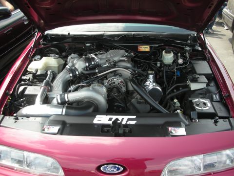 1992 Ford Crown Victoria - The engine bay of a maroon 1992 Ford Crown Victoria is visible with a prominent turbocharger and custom modifications.