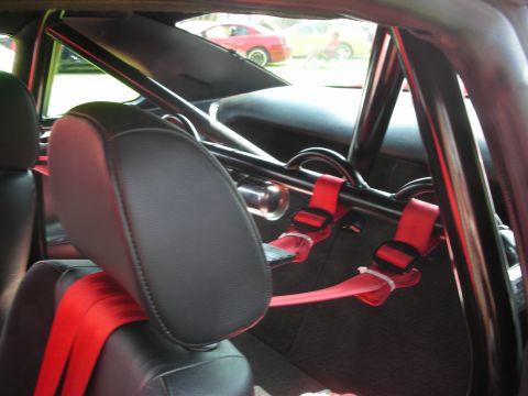1992 Ford Crown Victoria - View of a car's interior with racing modifications, including a roll cage and red harnesses.