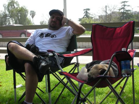 1992 Ford Crown Victoria - A man relaxes in a lawn chair while a pug naps in another chair outdoors.