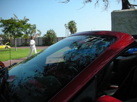 1992 Ford Crown Victoria - A woman walks past a yellow car while a red convertible's interior is shown with a reflection in the windshield.