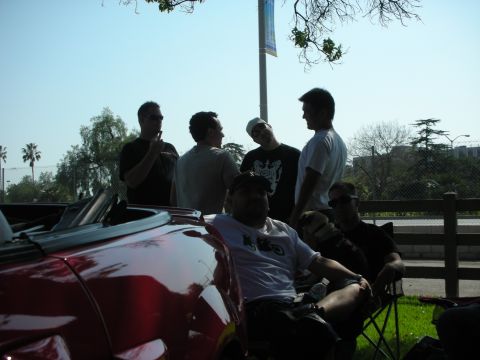 1992 Ford Crown Victoria - A group of men gather around a red convertible on a sunny day.
