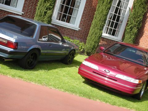 1992 Ford Crown Victoria - A red 1992 Ford Crown Victoria is parked on the grass next to a blue car.
