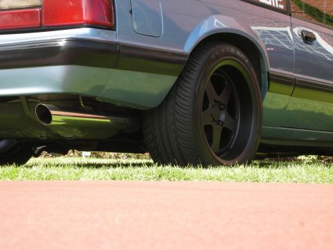 1992 Ford Crown Victoria - Rear view of a light blue car with a chrome exhaust pipe and black aftermarket wheels.