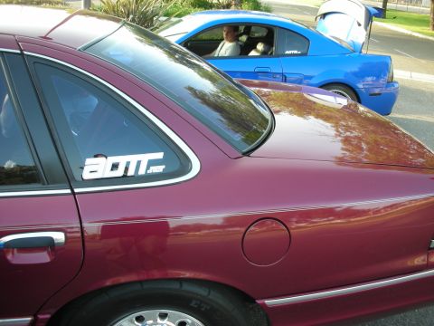 1992 Ford Crown Victoria - Two cars are parked side-by-side, with the maroon sedan in the foreground and a blue coupe behind it.