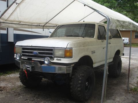 1989 Ford Bronco - This 1987 Ford Bronco has a winch and aftermarket bumper, and is parked under a tarp.