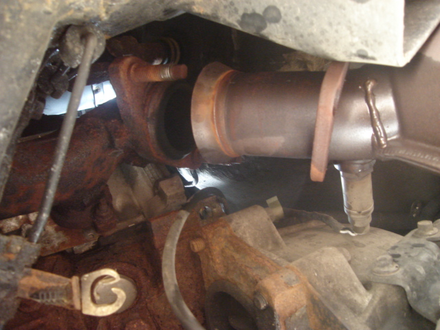 close-up of rusty exhaust pipe and catalytic converter connection