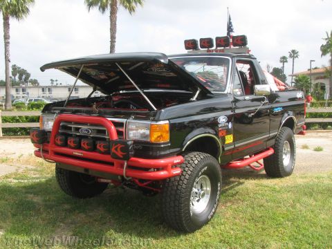 1968 Ford Mustang - Modified black Ford F-Series truck with hood open, custom red accents and off-road tires.