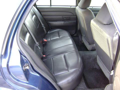 2001 Ford Crown Victoria - The rear interior of a blue car shows black leather seats and dark carpeting.