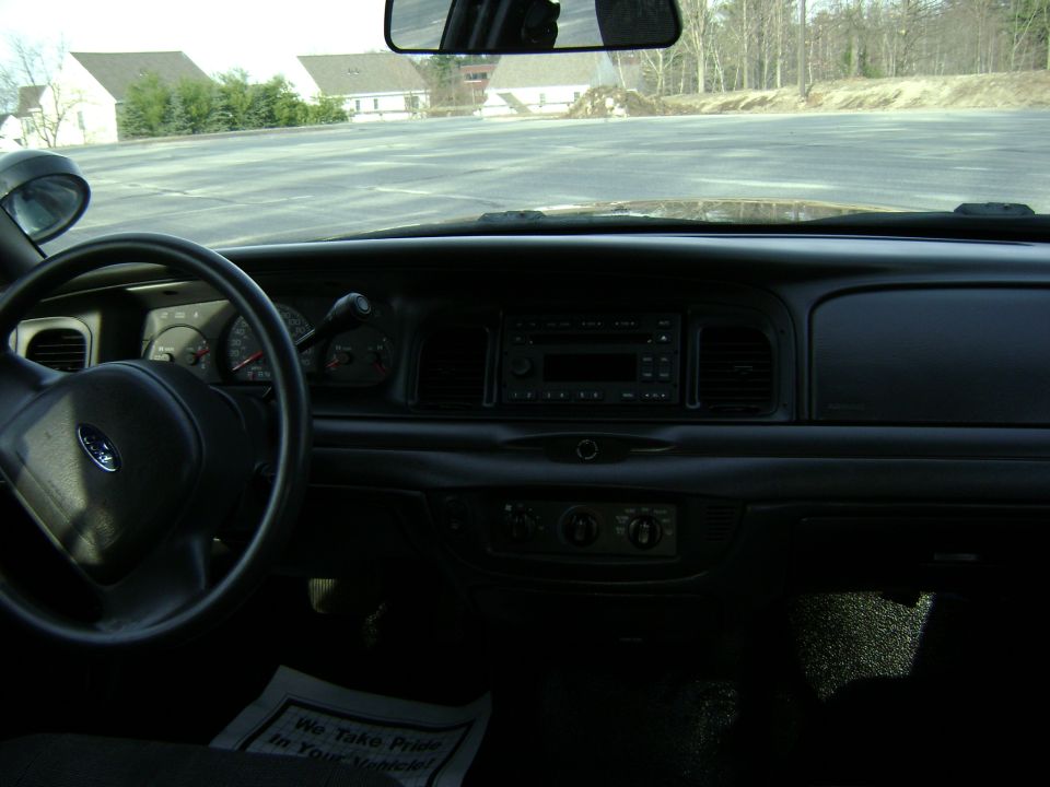 2001 Ford Crown Victoria interior showing steering wheel, dashboard, radio, and floor mat with text