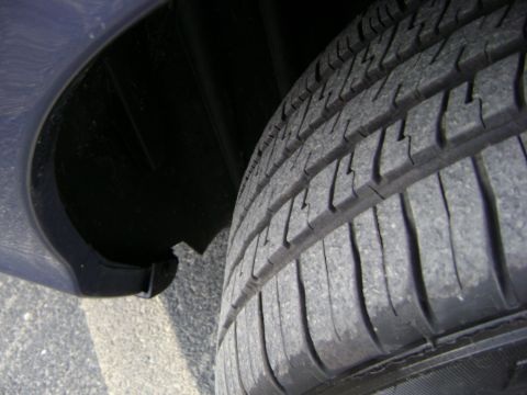 2001 Ford Crown Victoria - Close-up view of a car's tire and the dark interior of its wheel well.
