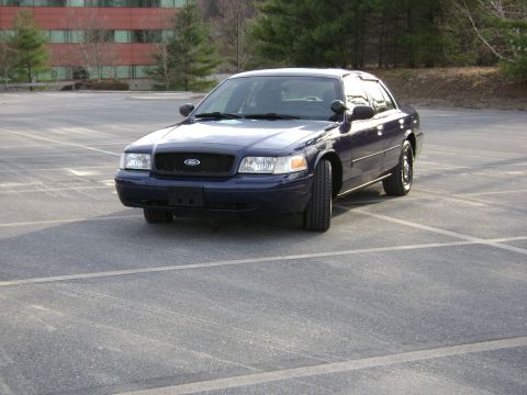 2001 Ford Crown Victoria - This dark blue 2001 Ford Crown Victoria sedan is shown from a three-quarter front view in an empty parking lot.