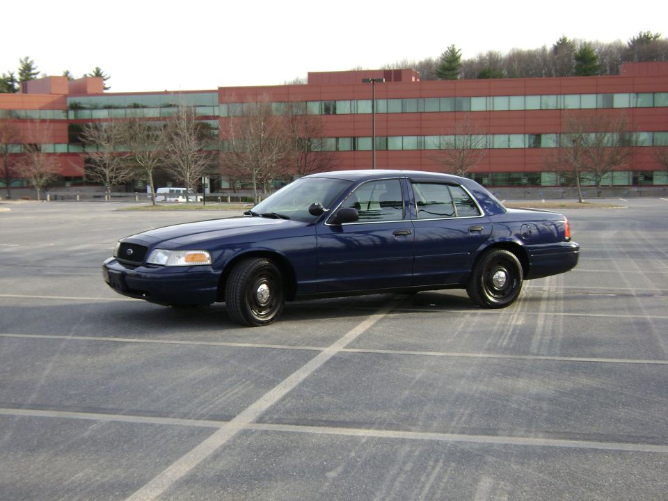 Dark blue 2001 Ford Crown Victoria sedan parked in an empty lot, side view