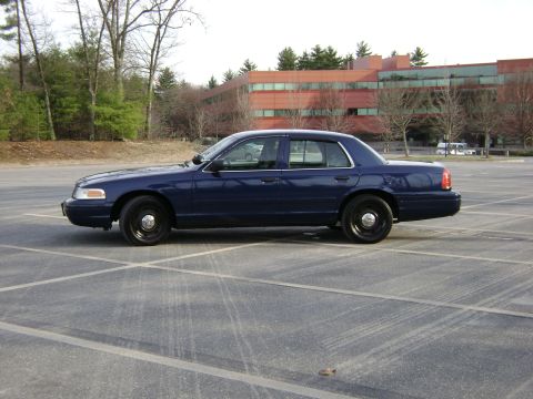 2001 Ford Crown Victoria - Side profile of a dark blue 2001 Ford Crown Victoria sedan parked in an empty lot.