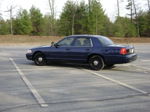 2001 Ford Crown Victoria - Dark blue 2001 Ford Crown Victoria police sedan parked in an empty lot.