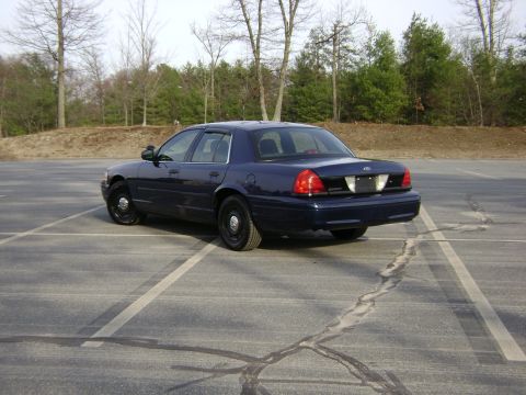 2001 Ford Crown Victoria - This sedan is parked in a lot with trees in the background.
